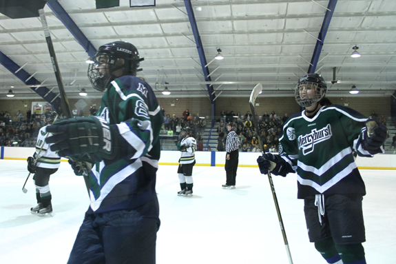 Ethan Magoc photo: Mercyhurst College's Melissa Lacroix, left, and Cassea Schols skate past their teammates on the bench after Jesse Scanzano's second period goal against Wayne State on Saturday, Feb. 5, 2011, at the Mercyhurst Ice Center.